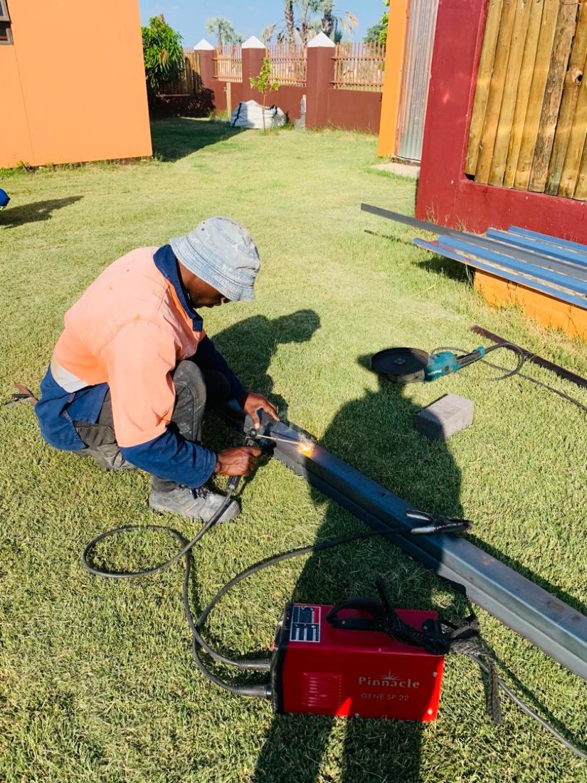 Welder working on fence rails outdoors