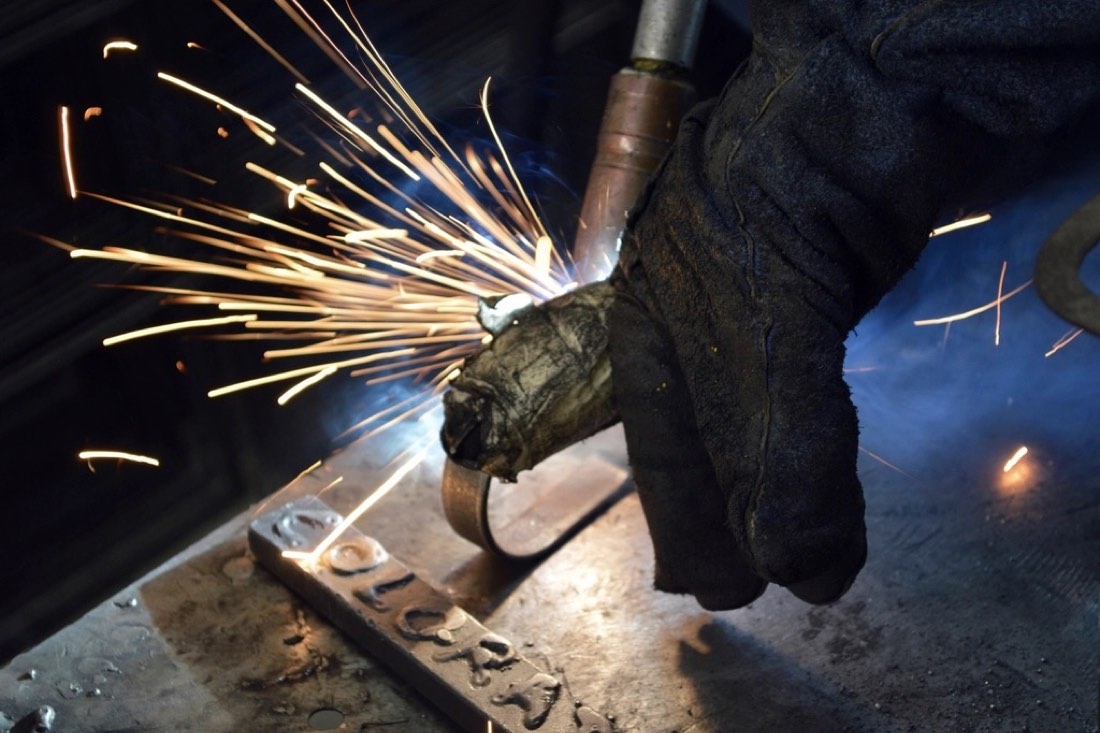 Grinder smoothing a weld on steel plate
