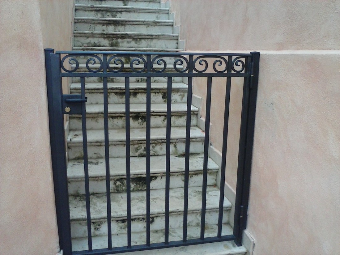 Black steel gate at the foot of concrete stairs